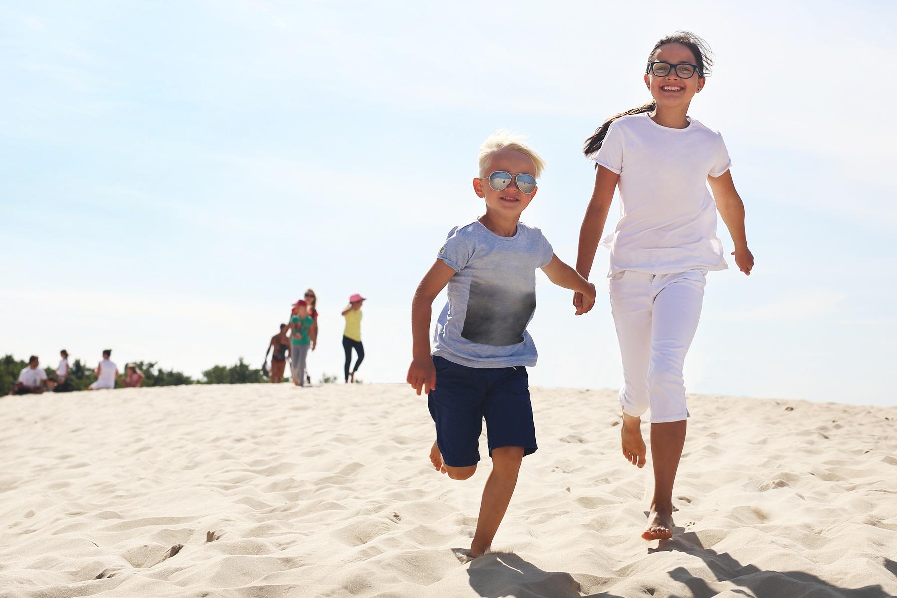 obozy dla dzieci nad morzem Radosna grupa nastolatków na plaży podczas wschodu słońca, ilustrująca jak wyglądają pełne wrażeń wakacje na obozy letnie nad polskim morzem.